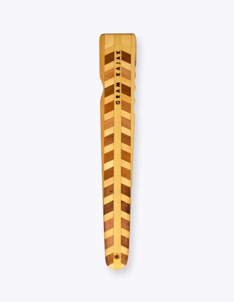 Gram 6120 norsaq throwing stick laminated in a chevron pattern of light wood tones, with finger grooves